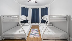 A room with two bunk beds, a ceiling fan, and a patterned rug. - Huge Home | Sleeps 10+ | Minutes from NYC (Bayonne)
