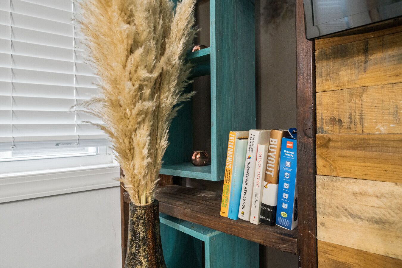 A bookshelf with books and a decorative vase.