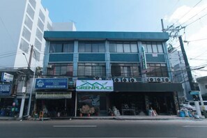 Un edificio de varios pisos con escaparate identificado como 'GREENPLACE' y un anuncio que dice 'TRADING'.