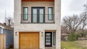 Una casa moderna de dos pisos con techo plano, un porche delantero de madera y un garaje.