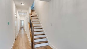 Un estrecho pasillo con una escalera de madera que sube a un piso superior.