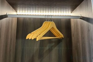 A wooden hanger rack with multiple hangers against a wooden wall. - Chambers Residence by Manhattan Group (Kuala Lumpur)