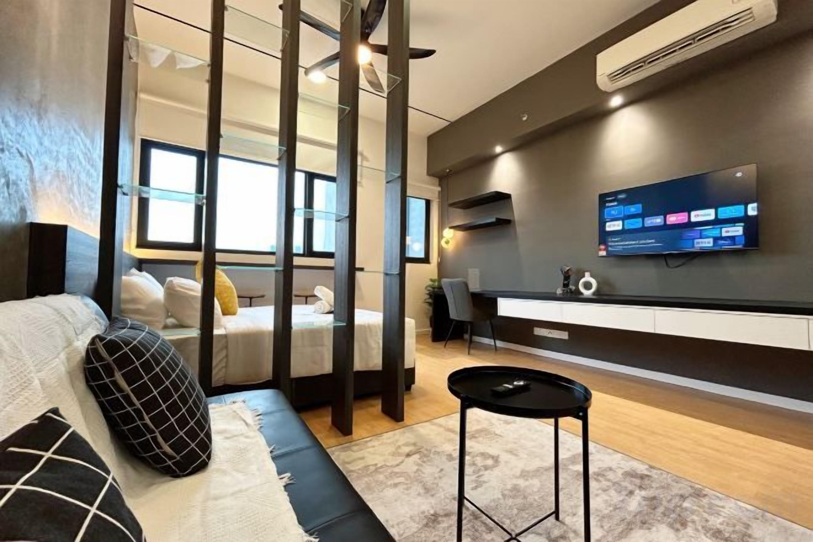 A modern room with a bed, a desk, a TV, and a sofa.