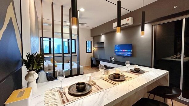 A modern kitchen with a marble countertop, black chairs, and a flat-screen TV mounted on the wall. - Chambers Residence by Manhattan Group (Kuala Lumpur)
