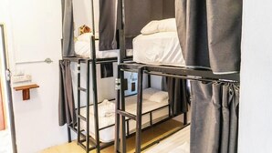 A dormitory room with bunk beds, grey curtains, and a small shelf with toiletries. - Vang Vieng Chill House (Vang Vieng)