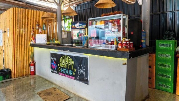 A bar area with a 'Happy Hour' sign, a counter with various items, and a fire extinguisher. - Vang Vieng Chill House (Vang Vieng)