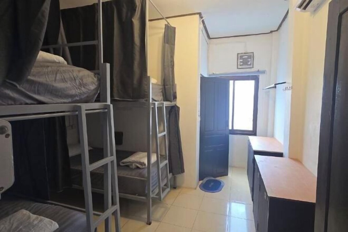 A bunk bed room with a desk and a small window.