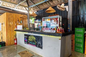 A counter with a sign that reads 'HAPPY HOUR' and a display case with various items. - Vang Vieng Chill House (Vang Vieng)