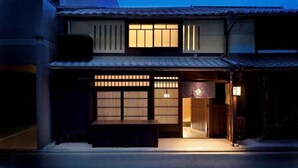 Un edificio japonés tradicional con fachada de madera, puertas correderas y un pequeño espacio de estar al aire libre.