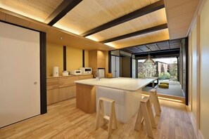 Une cuisine moderne dotée d’un îlot central, de planchers en bois et offrant une vue sur l’extérieur.