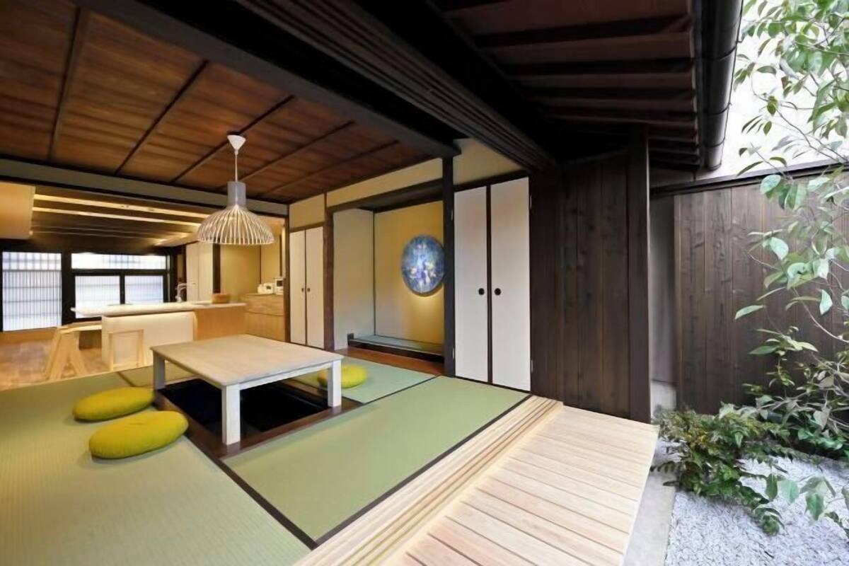 A traditional Japanese room with tatami flooring, a low wooden table, and a hanging light fixture.