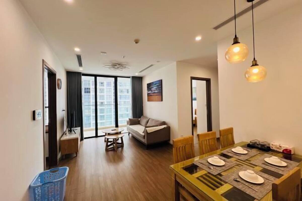 Uma sala de estar moderna com um sofá, mesa de jantar e cadeiras. Há uma grande janela com vista para a cidade.