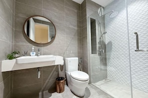 A bathroom with a toilet, sink, mirror, and shower.
