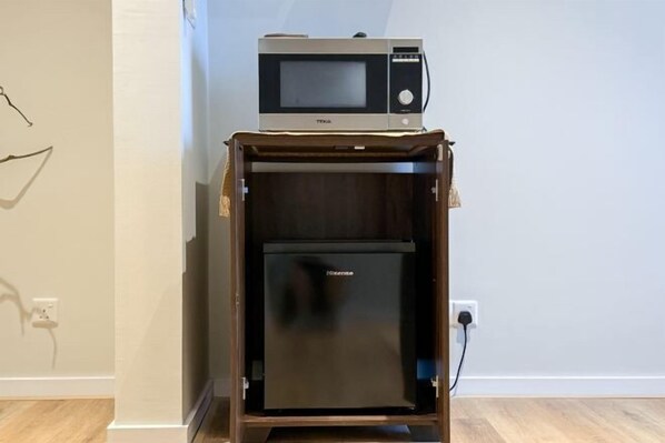 Un espace cuisine compact comprenant un four à micro-ondes et un réfrigérateur.