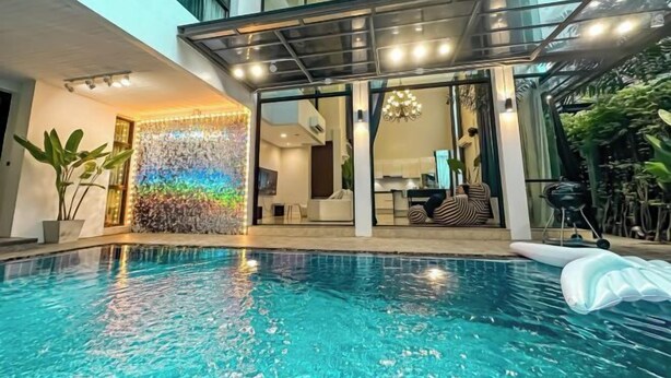 A modern indoor pool area with a clear pool, a covered seating area, and a glass wall with a colorful light installation. - 189/7bangkok 6 bedrooms private pool villa，1000square summer villa (Bangkok)
