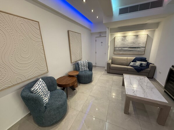 A modern living room with a sofa, two armchairs, a coffee table, and artwork on the walls. - Casa Azul : Walk to the beach apartment : King bed (Condado)