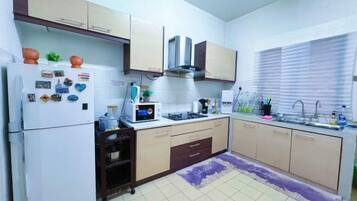 Una cocina compacta equipada con refrigerador, microondas, estufa y lavamanos.