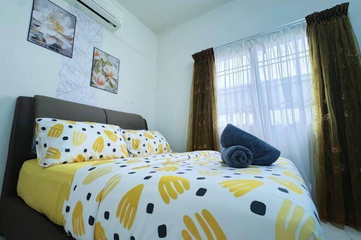 A bedroom with a bed, pillows, a blanket, a window with curtains, and wall art.