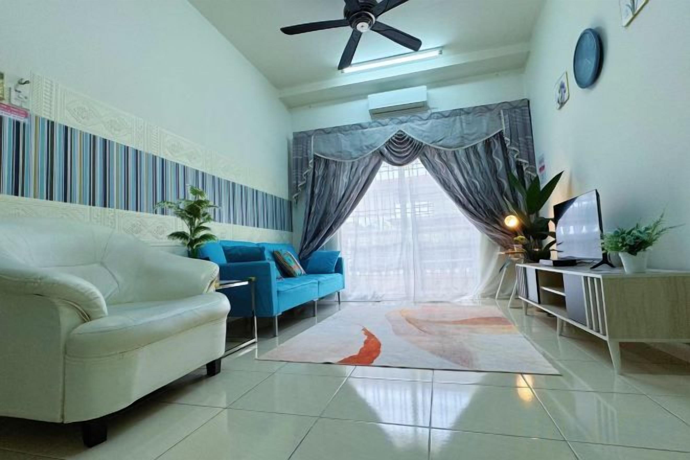 A living room with a white sofa, a blue sofa, a TV on a stand, and a ceiling fan.
