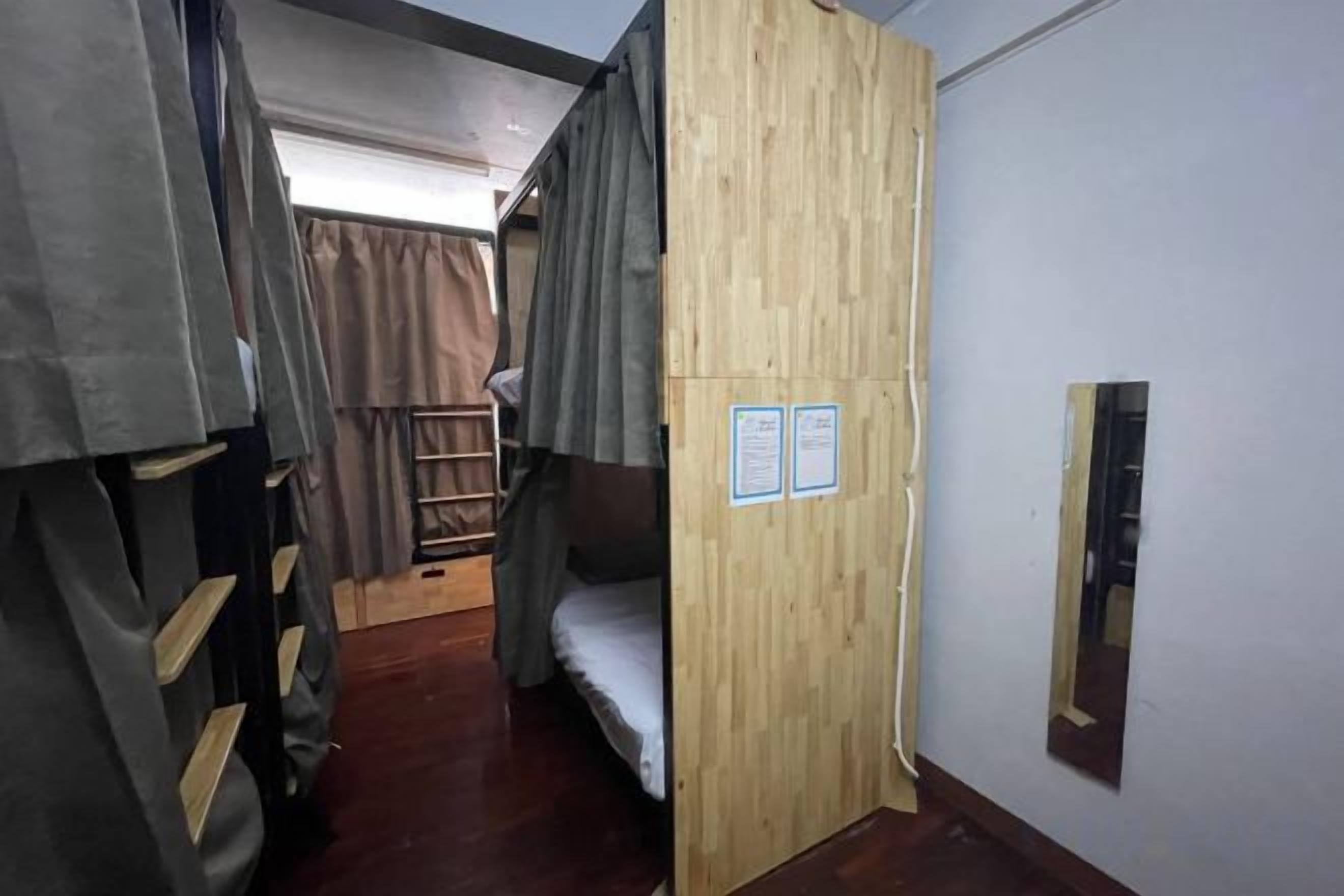A narrow corridor with bunk beds on either side, wooden walls, and a small ladder.