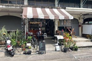 A storefront with a striped awning, potted plants, and a sign that reads 'Happy Hope.' - Happy Hope (Bangkok)