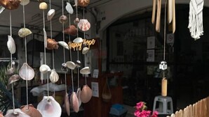 Un escaparate con caracolas colgantes y un letrero de neón que dice 'happy home'.