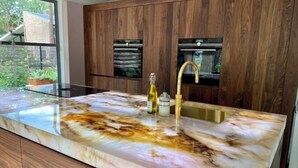 Una cocina con una amplia encimera de mármol, armarios de madera y horno empotrado.