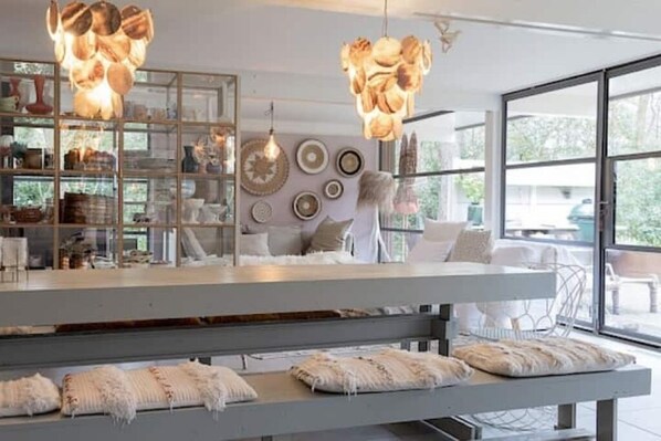 A modern interior with a glass display case, a white bench, and a large window. - Romantic Villa in the Woods—Dunes—Beach (Bergen)