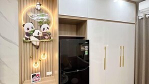 Una cocina con un refrigerador negro, armarios de madera y una lámpara con motivos de panda.