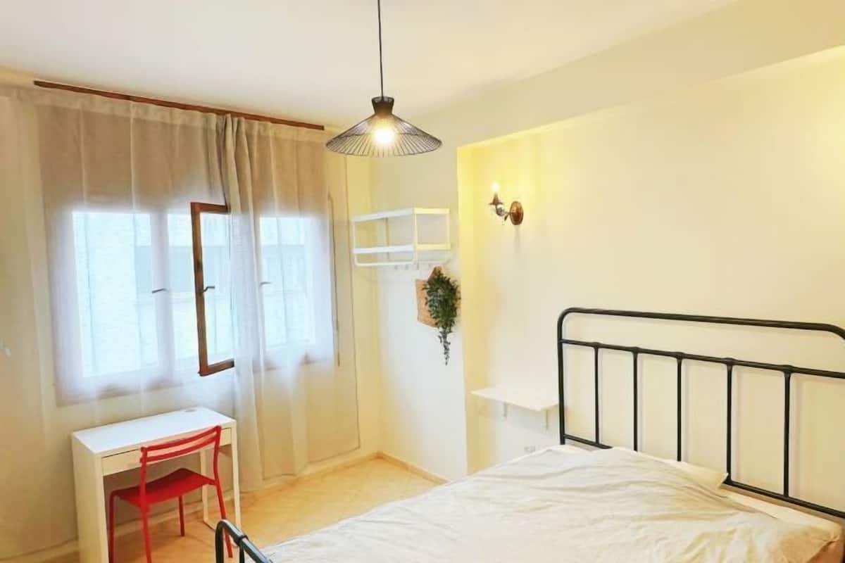 A bedroom with a bed, a desk, and a chair.