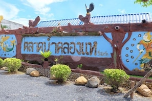 A decorative wall with Thai script and a bird sculpture. - Talad Nam Klong Hae Resort (Hat Yai)