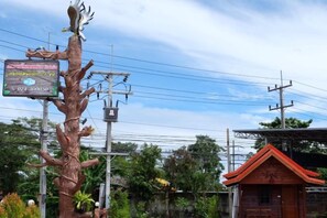 A tree-shaped sign with text, a power line structure, and a small building with a red roof. - Talad Nam Klong Hae Resort (Hat Yai)