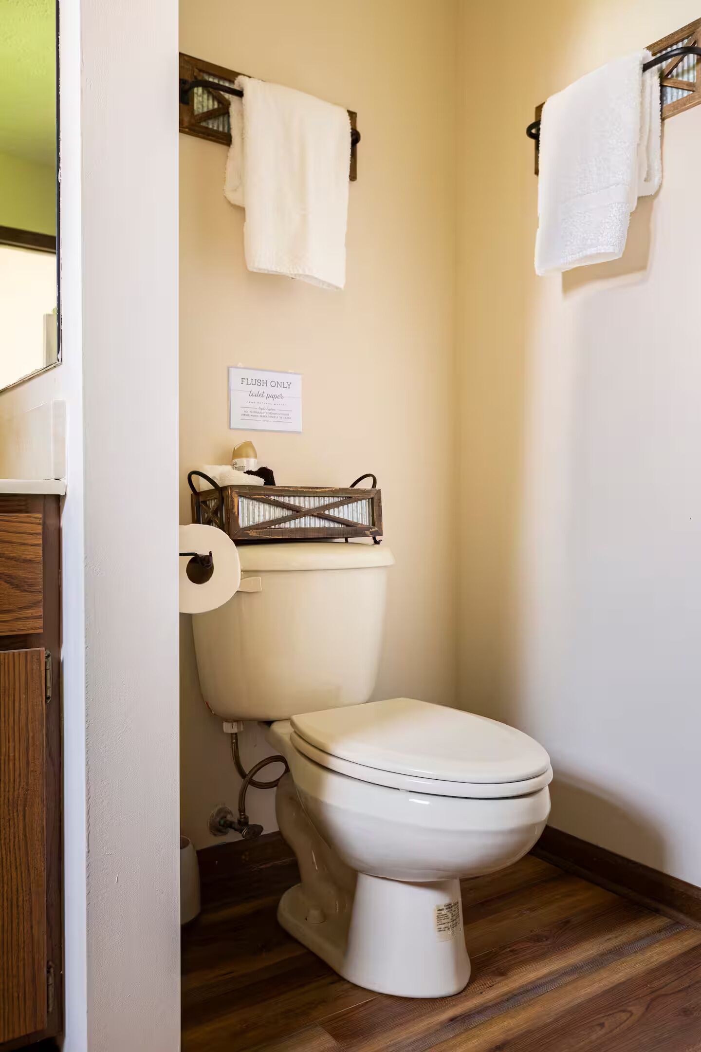 A small, compact bathroom with a toilet, a roll of toilet paper, and a sign indicating 'FLUSH ONLY.'