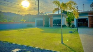 A building with a flat roof, a paved area in front, and a palm tree. - The Memories Hill Phuket (Phuket)