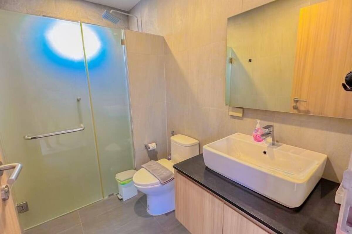 A modern bathroom with a glass shower enclosure, a white toilet, and a sink with a mirror above it.