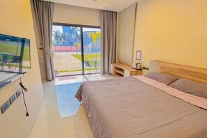 A hotel room with a large bed, a TV, a desk, and a sliding glass door to an outdoor area. - The Memories Hill Phuket (Phuket)