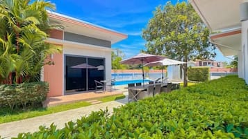 A modern building with a swimming pool, outdoor seating, and a covered patio area.