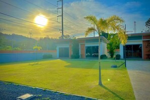 A building with a grassy lawn, a palm tree, and a clear sky. - The Memories Hill Phuket (Phuket)
