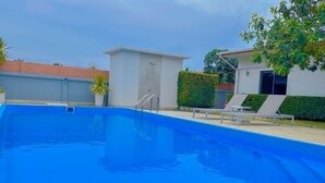 A swimming pool with a clear blue water, surrounded by a white building with a small window and a door. There are two lounge chairs and a potted plant near the pool. - The Memories Hill Phuket (Phuket)