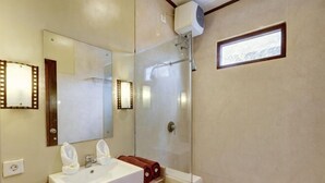 Ένα μπάνιο με έναν μεγάλο καθρέφτη, έναν νιπτήρα, ένα ντους και μια κρεμάστρα για πετσέτες.
