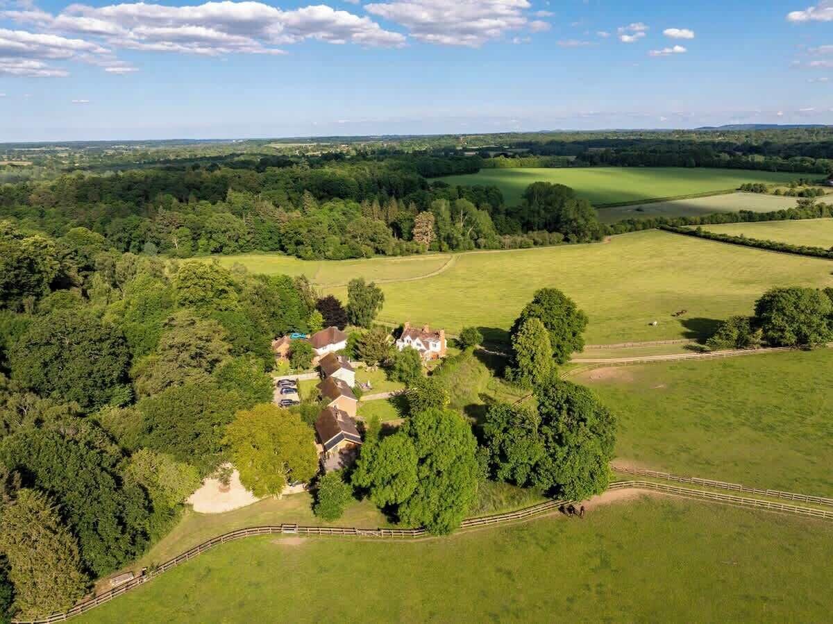 An aerial view of a rural property with multiple buildings, open fields, and a fenced area.