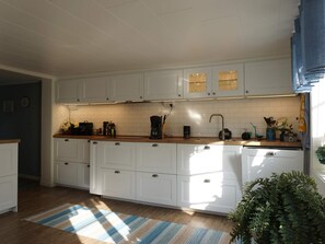 A modern kitchen with white cabinets, a wooden countertop, and a striped rug. - 6 Person Holiday Home in Lysekil (Lysekil)
