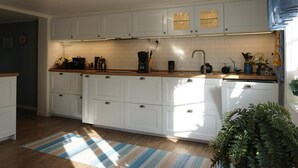 A modern kitchen with white cabinets, a wooden countertop, and a striped rug. - 6 Person Holiday Home in Lysekil (Lysekil)