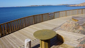 A wooden deck with a table and benches overlooking a body of water. - 6 Person Holiday Home in Lysekil (Lysekil)