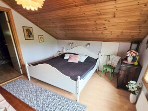 A bedroom with a bed, a nightstand, a green chair, a dresser, and a wall-mounted lamp. - 6 Person Holiday Home in Lysekil (Lysekil)
