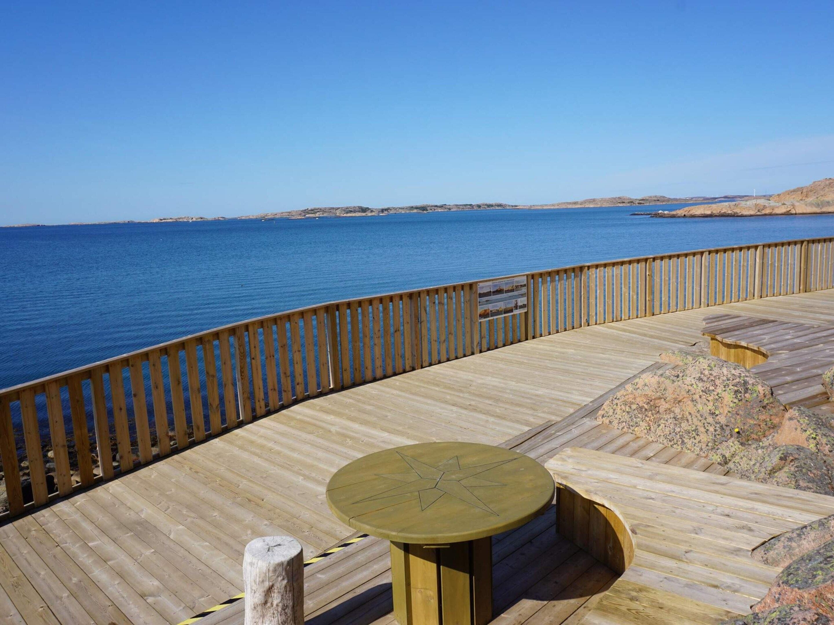 A wooden deck with a table and benches overlooking a body of water.