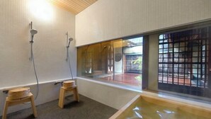 Une salle de bain moderne avec une grande fenêtre, deux tabourets en bois et une baignoire.