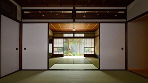 A traditional Japanese room with tatami flooring, sliding doors, and a view of greenery outside. - Kyo No Ondokoro Nishijin Villa #5 (Kyoto)