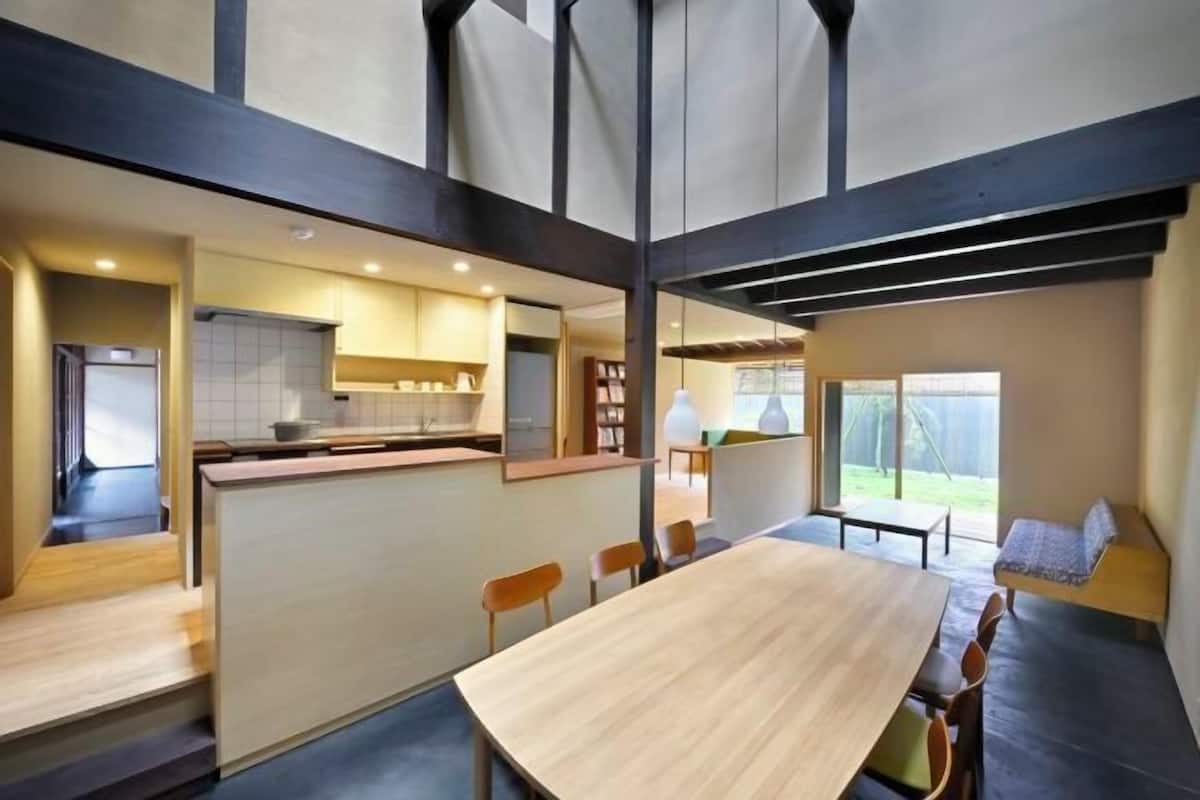A modern interior with a dining area, kitchen, and seating by a window.
