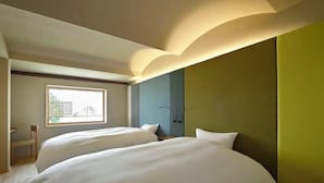 Une chambre d’hôtel avec deux lits, une fenêtre, une chaise et un mur d’accent vert.